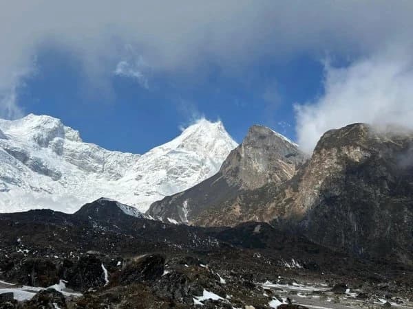 Traditional Buddhist chortens in the Manaslu Circuit Trek region with eroded cliffs and Himalayan mountains.