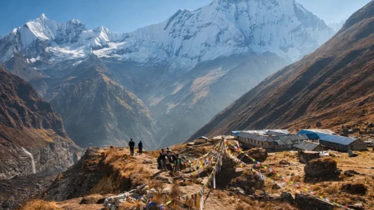 Annapurna Base Camp trekking trail with Himalayan village, prayer flags, and snow-capped peaks in annapurna region, Nepal.