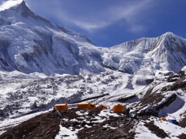 Traditional Buddhist chortens in the Manaslu Circuit Trek region with eroded cliffs and Himalayan mountains.
