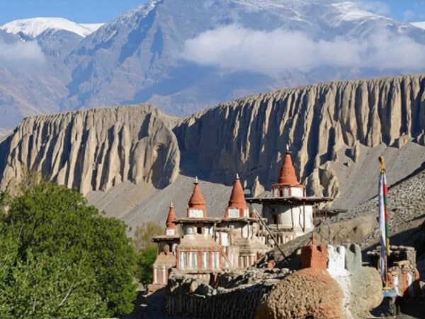 Ancient Buddhist stupas in front of large desert cliffs in Upper Mustang, Nepal.
