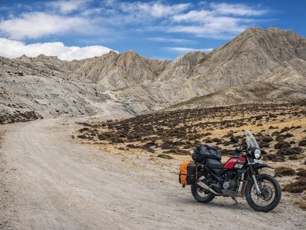 Single adventure motorbike on a remote Himalayan dirt road with dramatic rocky mountains in Nepal