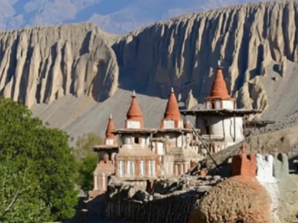 Ancient Buddhist stupas in front of large desert cliffs in Upper Mustang, Nepal.
